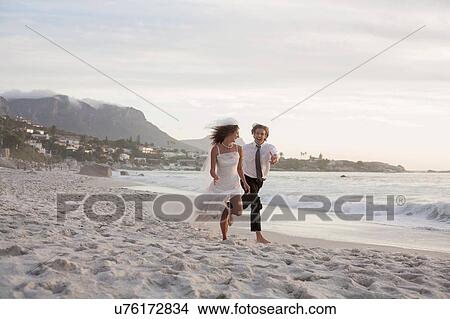 Picture - Bride and groom running along beach. Fotosearch