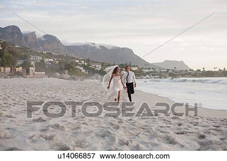 Bride and groom running along beach View Large Photo Image Stock Photo - Bride and groom running along beach. Fotosearch