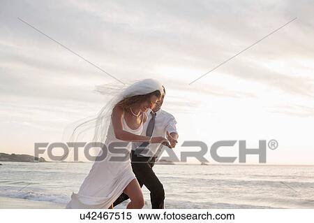 Bride and groom running along beach View Large Photo Image Stock Photography - Bride and groom running along beach. Fotosearch