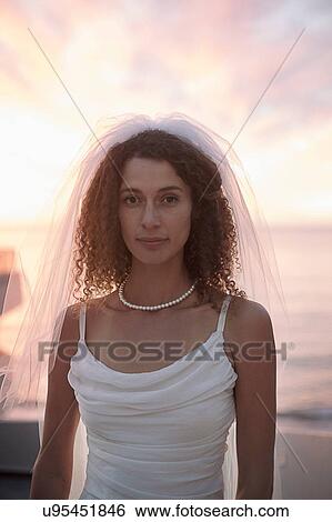 Bride standing on beach against sunset View Large Photo Image Stock Photograph - Bride standing on beach against sunset. Fotosearch