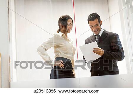 Stock Photograph - Businessman and businesswoman looking at documents, having conversation. Fotosearch