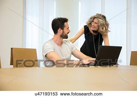 Businesswoman talking to male designer in office View Large Photo Image Stock Image - Businesswoman talking to male designer in office. Fotosearch