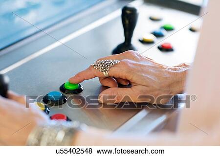 Stock Photo - Close up of senior womans hand pressing button on games machine. Fotosearch