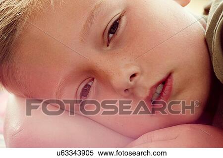 Stock Photography - Close up portrait of boy lying down looking at camera. Fotosearch