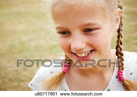 Stock Image - Close up portrait of girl with pigtails looking away smiling. Fotosearch