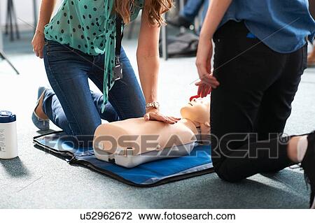 Stock Image - College student performing CPR on mannequin in class. Fotosearch
