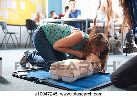 Stock Photography - College student performing CPR on mannequin in class. Fotosearch