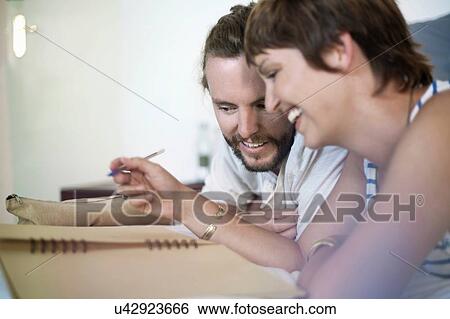 Stock Photograph - Couple chatting and writing in bed. Fotosearch