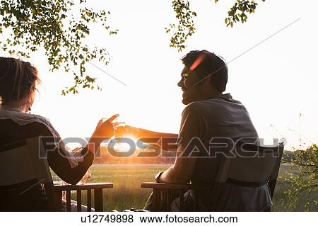 Stock Photo - Couple drinking wine at sunset at safari lodge, Kafue National Park, Zambia. Fotosearch