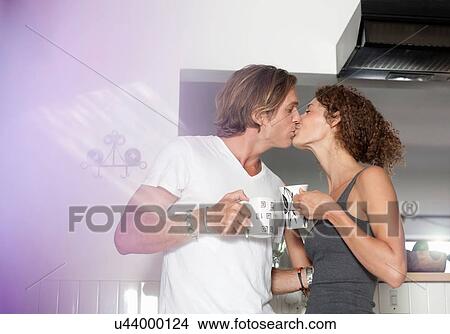 Couple in sleepwear, in kitchen, drinking coffee, kissing View Large Photo Image Picture - Couple in sleepwear, in kitchen, drinking coffee, kissing. Fotosearch