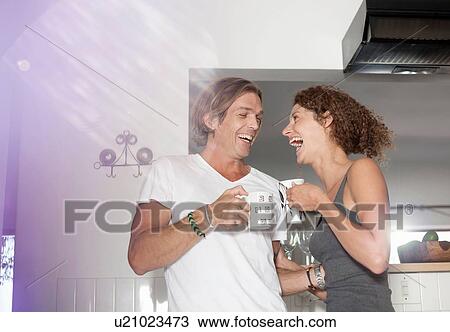 Couple in sleepwear, in kitchen, drinking coffee, laughing View Large Photo Image Stock Image - Couple in sleepwear, in kitchen, drinking coffee, laughing. Fotosearch