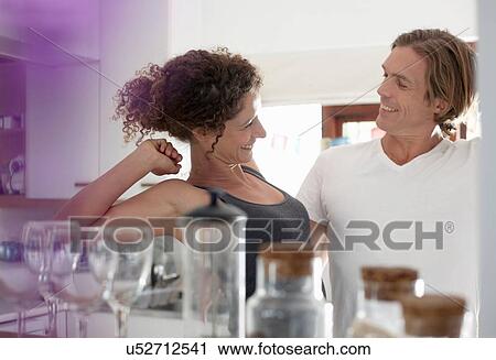 Stock Image - Couple in sleepwear, in kitchen, stretching, smiling. Fotosearch