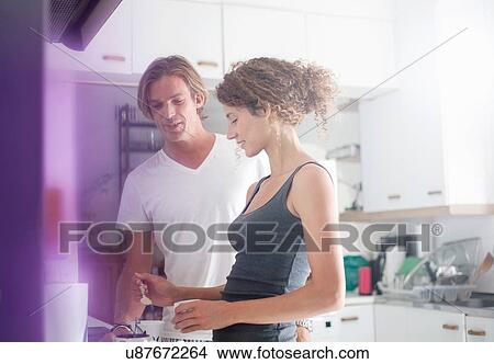 Picture - Couple in sleepwear, making coffee in morning. Fotosearch
