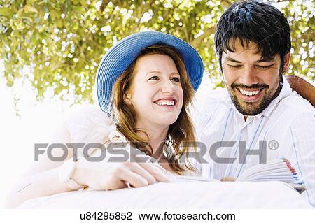 Stock Image - Couple reading guidebook at safari lodge, Kafue National Park, Zambia. Fotosearch