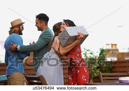 Couples meeting on roof terrace smiling, hugging holding gift View Large Photo Image Picture - Couples meeting on roof terrace smiling, hugging holding gift. Fotosearch