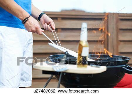 Cropped shot of mid adult man barbecuing at rooftop barbecue View Large Photo Image Stock Image - Cropped shot of mid adult man barbecuing at rooftop barbecue. Fotosearch