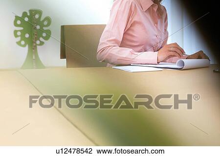 Stock Image - Cropped shot of young businesswoman making notes in office. Fotosearch