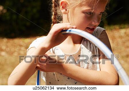 Cropped view of girl holding hula hoop looking down smiling View Large Photo Image Picture - Cropped view of girl holding hula hoop looking down smiling. Fotosearch