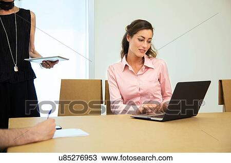 Stock Image - Design team meeting at boardroom table. Fotosearch