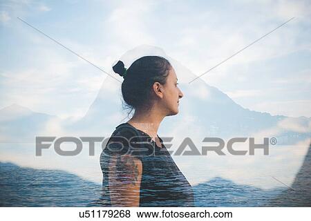 Stock Photo - Double exposure of mid adult woman looking out at Lake Lugano, Switzerland. Fotosearch