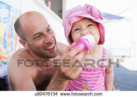 Father feeding toddler daughter ice cream cone on beach View Large Photo Image Picture - Father feeding toddler daughter ice cream cone on beach. Fotosearch