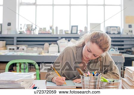 Stock Photo - Female print designer working on sketchbook in workshop. Fotosearch