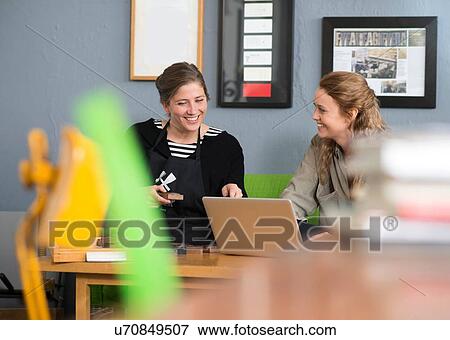Stock Photo - Female printer and designer using laptop in workshop office. Fotosearch