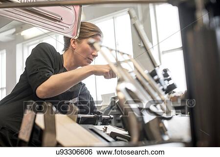 Stock Photograph - Female printer preparing machine in workshop. Fotosearch