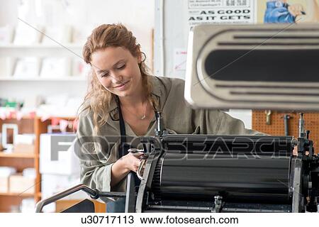 Stock Image - Female printer preparing printing machine in workshop. Fotosearch