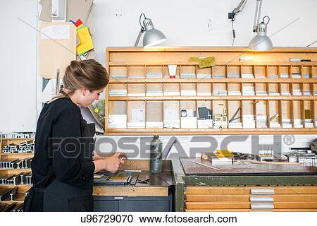 Stock Image - Female printer selecting letterpress letters in print workshop. Fotosearch