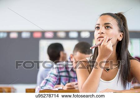 Female student, sitting at desk in classroom, thinking View Large Photo Image Picture - Female student, sitting at desk in classroom, thinking. Fotosearch