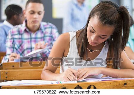 Female student, sitting at desk in classroom, writing View Large Photo Image Stock Image - Female student, sitting at desk in classroom, writing. Fotosearch