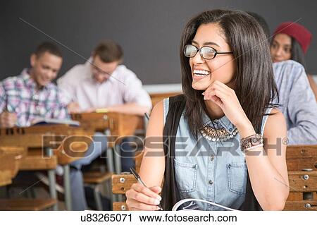Female student, sitting at desk in classroom, smiling View Large Photo Image Stock Image - Female student, sitting at desk in classroom, smiling. Fotosearch