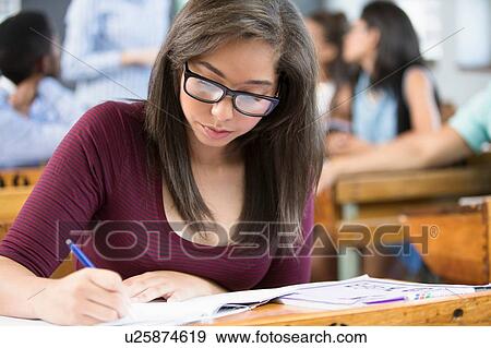 Female student, sitting at desk in classroom, writing View Large Photo Image Stock Photo - Female student, sitting at desk in classroom, writing. Fotosearch