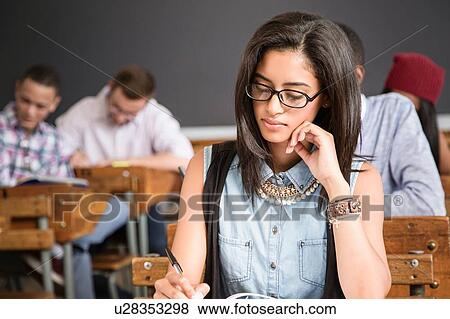 Female student, sitting at desk in classroom, writing View Large Photo Image Stock Photo - Female student, sitting at desk in classroom, writing. Fotosearch