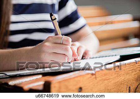 Stock Photo - Female student working in empty classroom, close up. Fotosearch