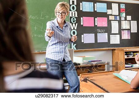 Stock Photo - Female teacher addressing students in classroom. Fotosearch
