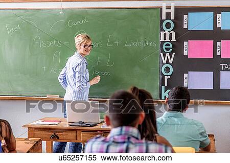 Stock Photography - Female teacher addressing students in classroom. Fotosearch