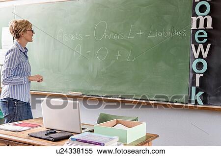 Female teacher in classroom, looking at words on blackboard View Large Photo Image Stock Photography - Female teacher in classroom, looking at words on blackboard. Fotosearch