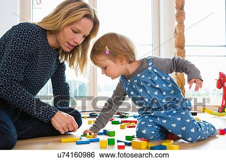 Female toddler and mother playing with building bricks on living room floor View Large Photo Image Stock Photograph - Female toddler and mother playing with building bricks on living room floor. Fotosearch