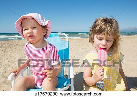 Female toddler and sister eating ice lollies on beach View Large Photo Image Stock Image - Female toddler and sister eating ice lollies on beach. Fotosearch
