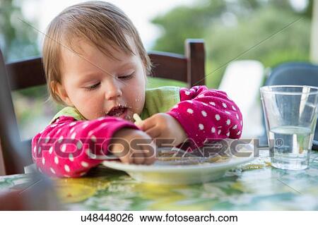Female toddler eating at table View Large Photo Image Stock Photograph - Female toddler eating at table. Fotosearch