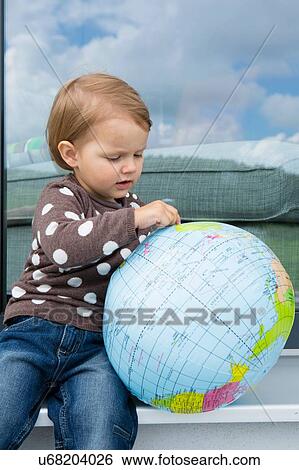 Female toddler playing with inflatable globe on windowsill View Large Photo Image Stock Photograph - Female toddler playing with inflatable globe on windowsill. Fotosearch