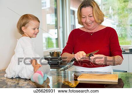 Female toddler sitting on kitchen counter watching grandmother View Large Photo Image Stock Image - Female toddler sitting on kitchen counter watching grandmother. Fotosearch