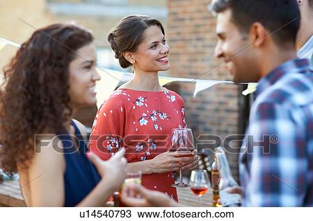 Stock Image - Friends at early evening party. Fotosearch