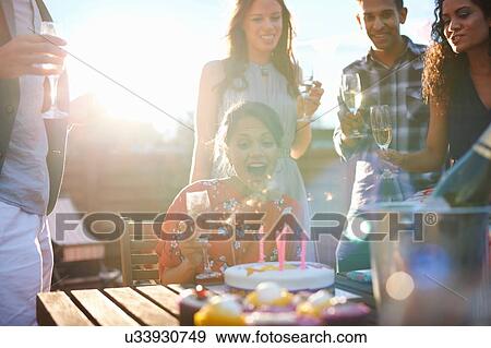Friends at outdoor party blowing out candles on cake View Large Photo Image Stock Photo - Friends at outdoor party blowing out candles on cake. Fotosearch