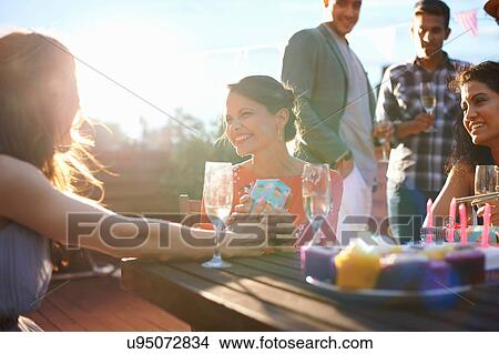 Friends at outdoor party sitting drinking champagne smiling View Large Photo Image Picture - Friends at outdoor party sitting drinking champagne smiling. Fotosearch