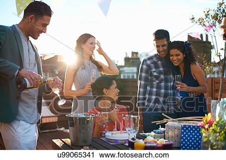 Friends at party on roof terrace pouring champagne View Large Photo Image Stock Image - Friends at party on roof terrace pouring champagne. Fotosearch
