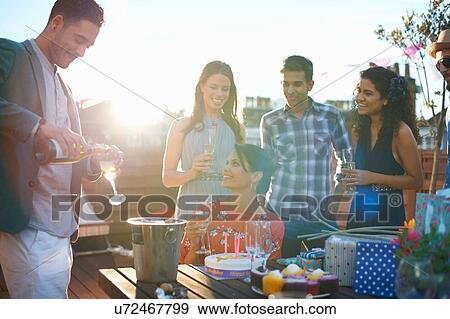 Friends at party on roof terrace pouring champagne View Large Photo Image Stock Photo - Friends at party on roof terrace pouring champagne. Fotosearch