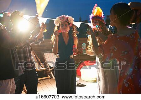 Friends blowing bubbles at party View Large Photo Image Stock Image - Friends blowing bubbles at party. Fotosearch